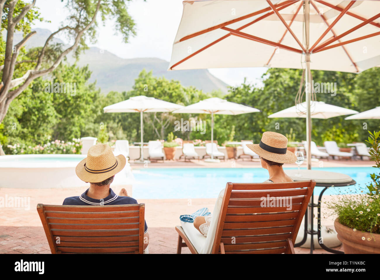 Couple relaxing on lounge chairs at sunny resort piscine Banque D'Images