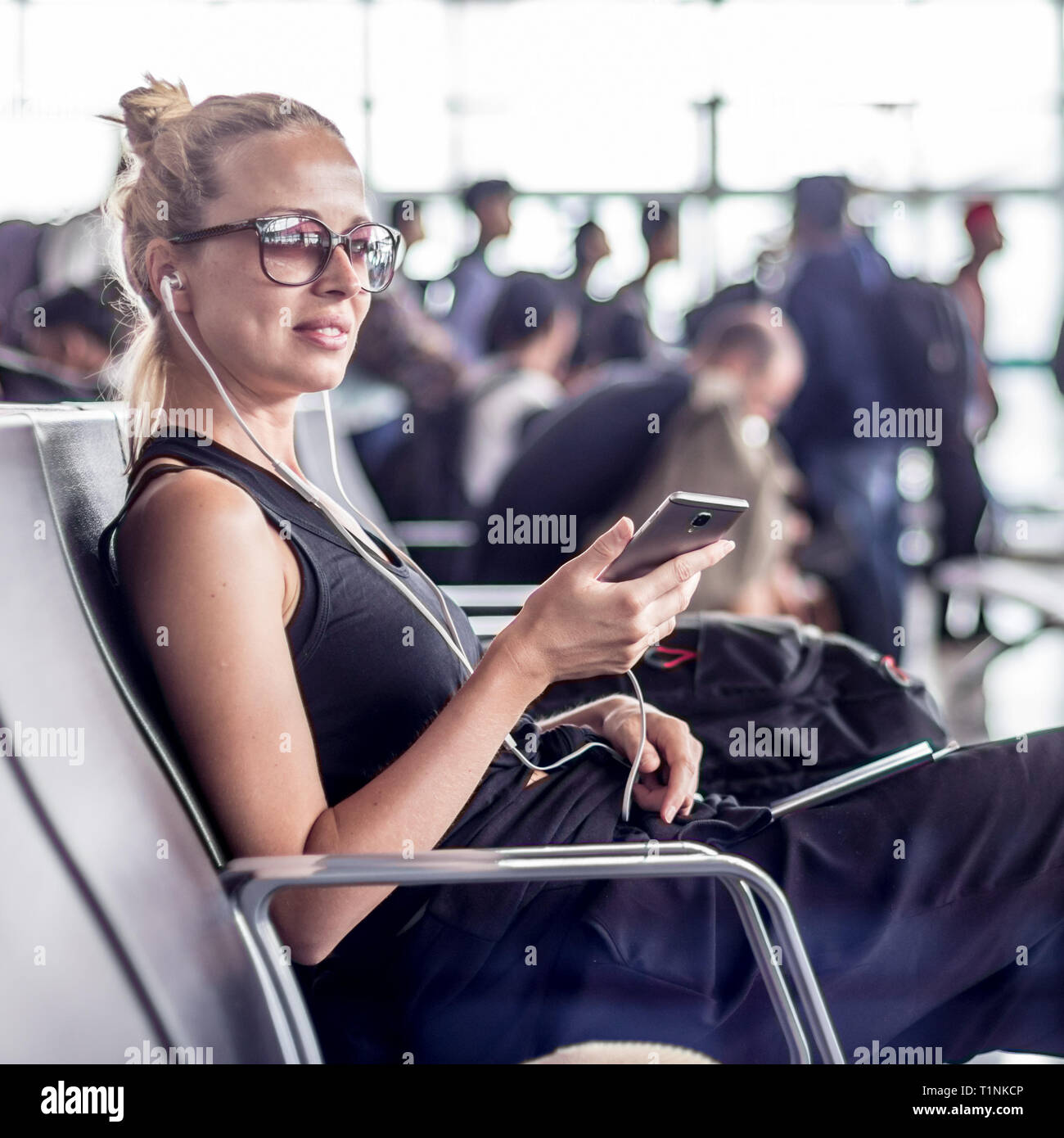 Female traveler talking on cell phone en attendant de monter à bord d'un avion à l'embarquement au terminal de l'aéroport d'Asie. Banque D'Images