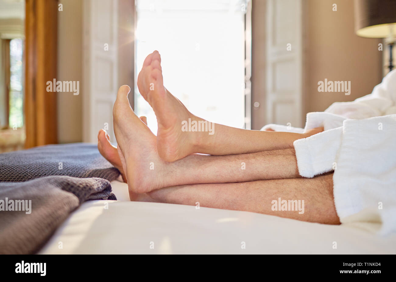 Barefoot couple relaxing on hotel bed Banque D'Images