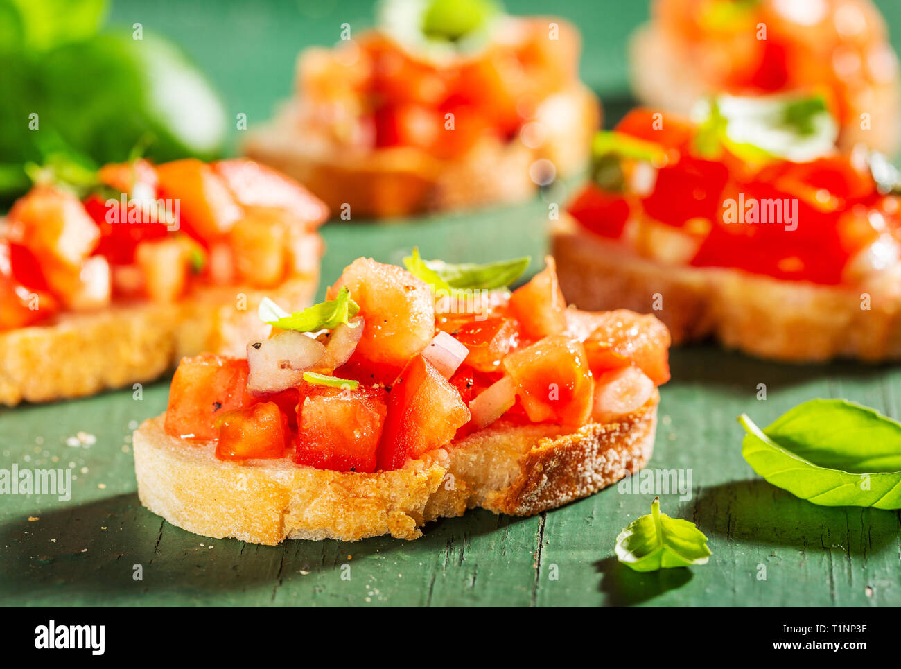 Bruschetta à la tomate, oignon, huile d'olive et le basilic sur fond de bois. Libre. Banque D'Images