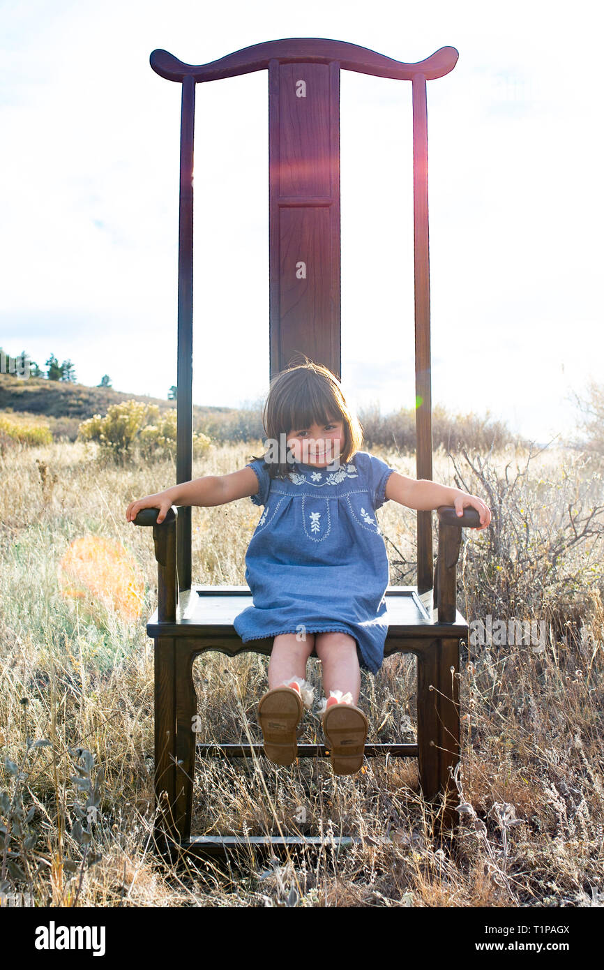 Fille assise dans un grand fauteuil dans le champ Banque D'Images