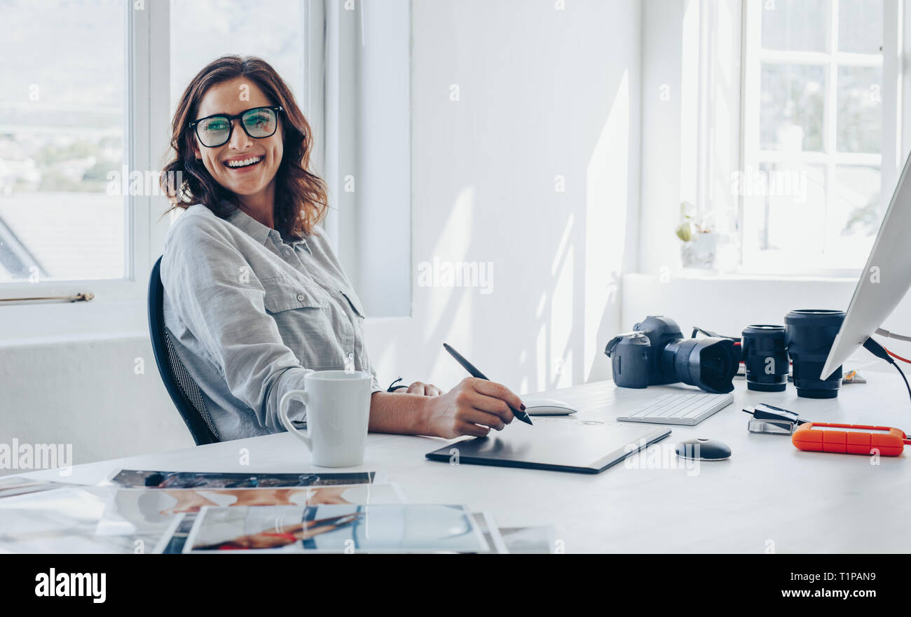 Photographe professionnel assise à son bureau à l'écart et souriant. Woman  in office avec tablette graphique et numérique stylo de dessin Photo Stock  - Alamy