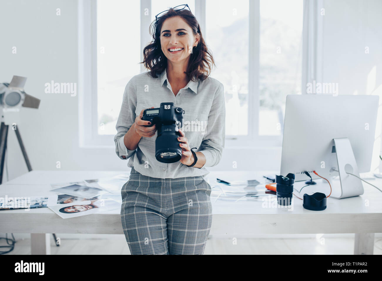 Jeune femme photographe avec un appareil photo professionnel de bureau. Femme photographe avec appareil photo numérique. Banque D'Images