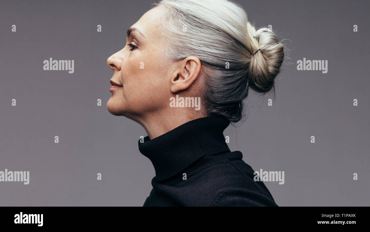 Vue latérale du senior woman sur fond gris. Voir le profil de mature woman in black occasionnels. Banque D'Images