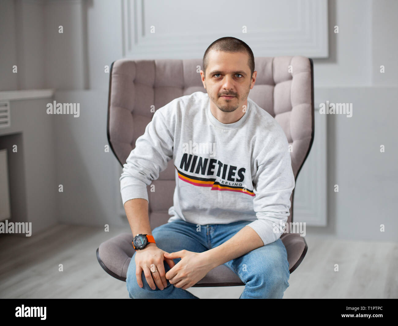 Portrait de l'homme à la caméra en tout assis sur une chaise Banque D'Images