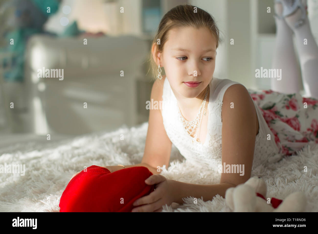 Très belle fille de l'adolescence sur un lit avec un cœur rouge pillow.Jeune femme Banque D'Images