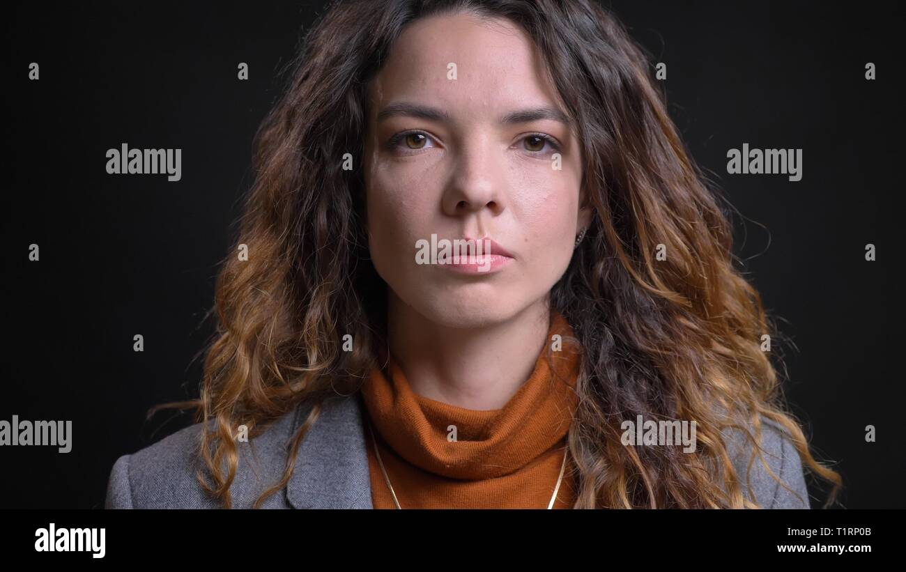De jeunes pousses closeup portrait of attractive avec visage de femme brune cheveux bouclés à tout droit au fond de l'appareil photo avec isolated on black Banque D'Images