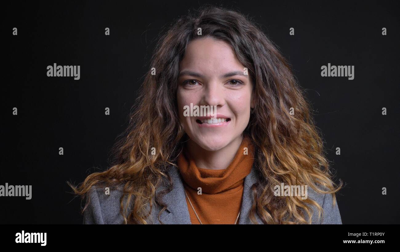 De jeunes pousses Gros plan femme caucasienne attrayant à la caméra à droite avec l'excitation et souriant joyeusement avec isolé sur fond noir Banque D'Images