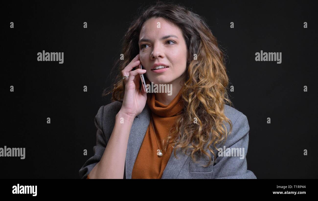 De jeunes pousses Gros plan femme caucasienne attrayant d'avoir une conversation au téléphone en face de la caméra avec isolé sur fond noir Banque D'Images