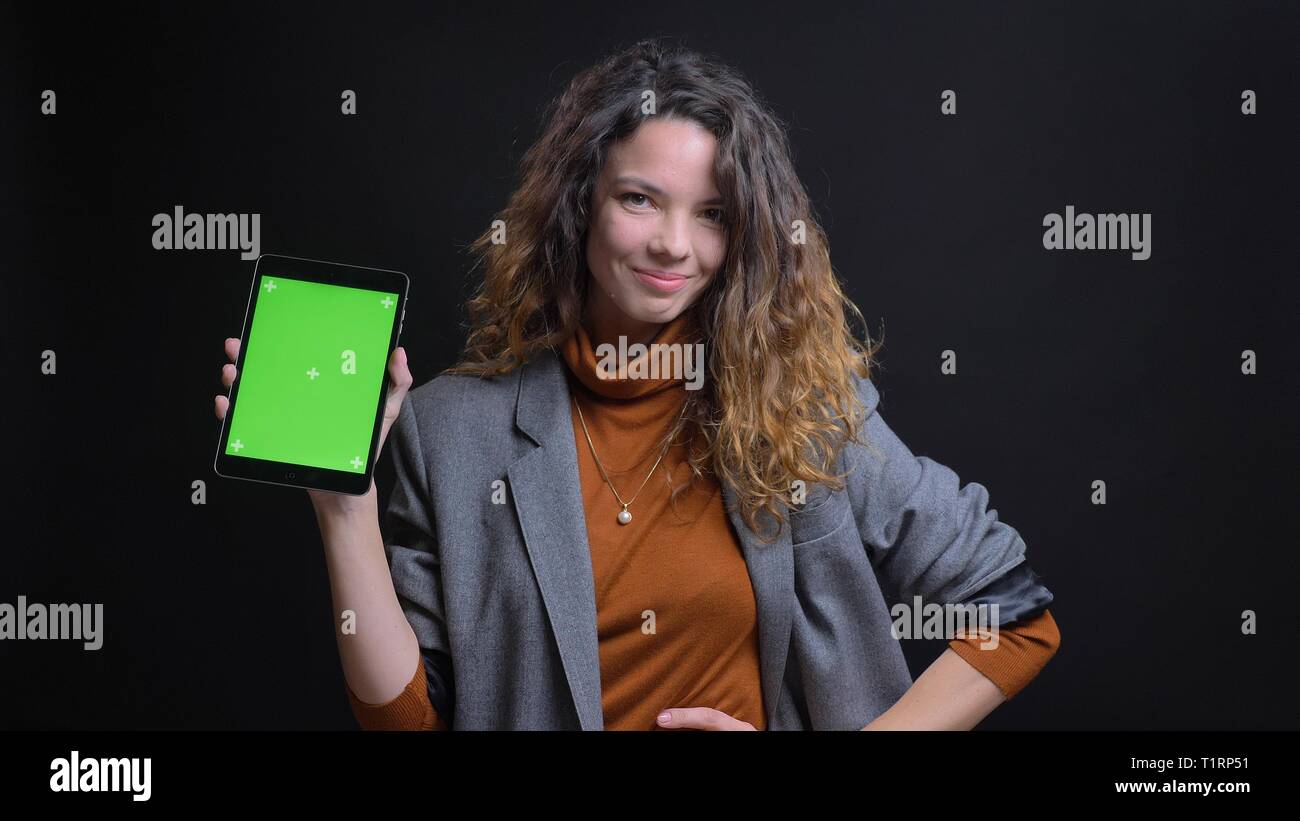 De jeunes pousses Gros plan pretty caucasian female en utilisant la tablette et montrant à l'écran vert avec caméra isolé sur fond noir Banque D'Images
