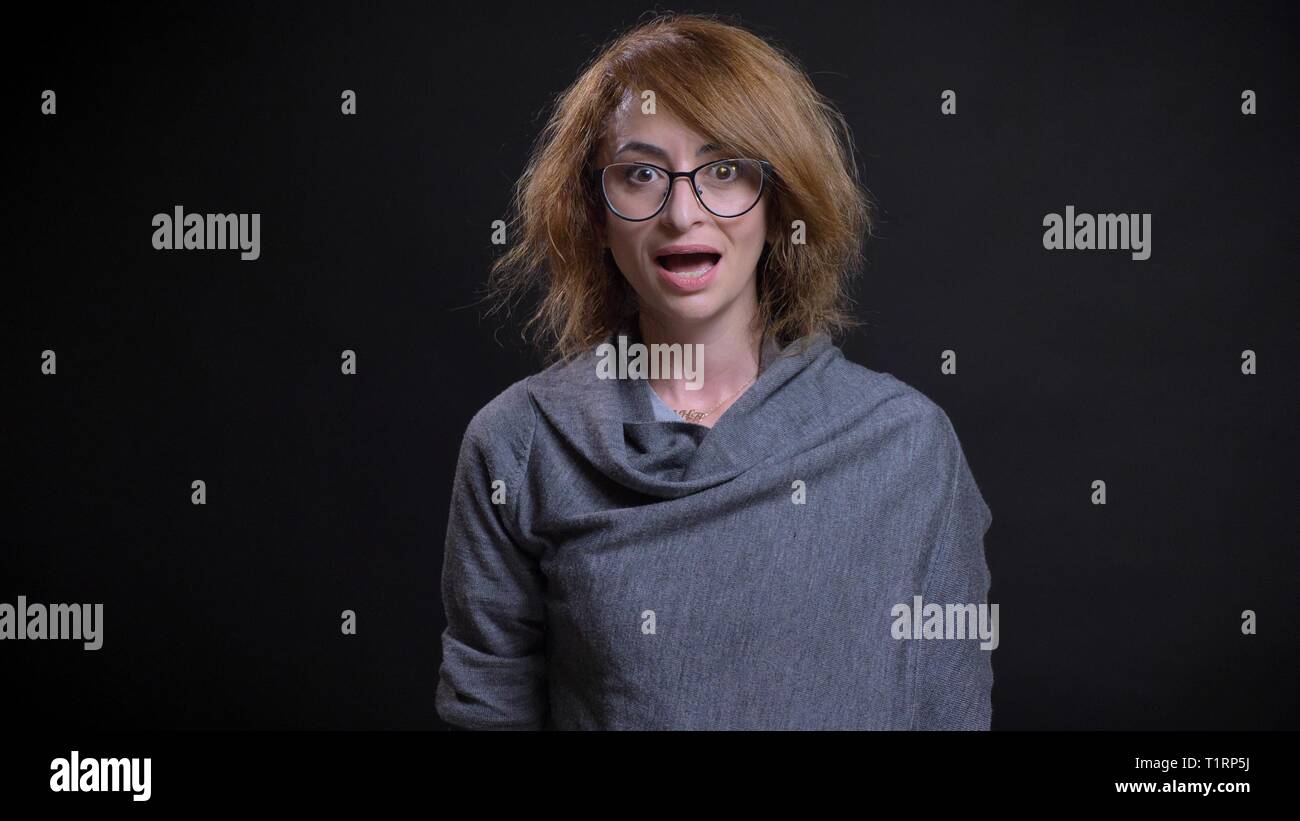 Closeup portrait of middle-aged femme rousse extravagante dans les verres se surpris et excité en regardant at camera Banque D'Images