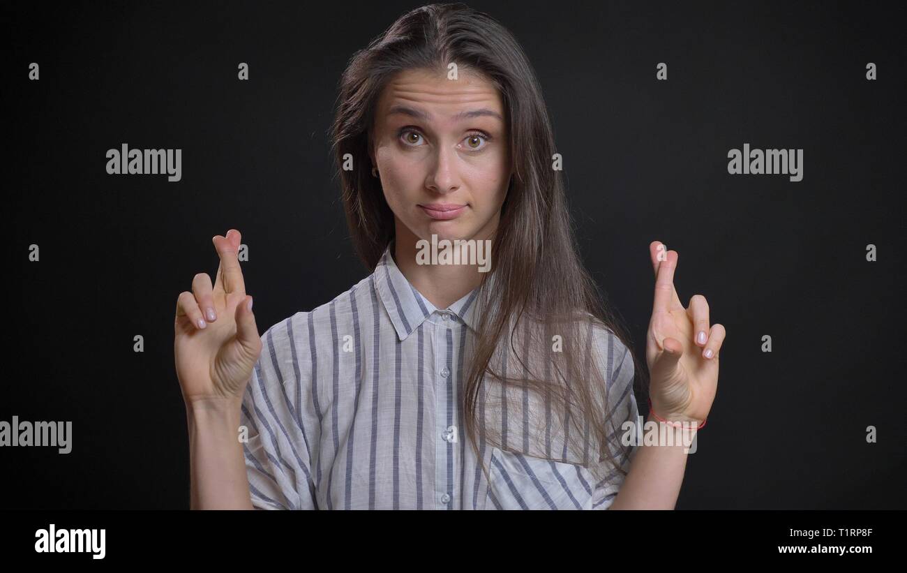 Closeup portrait de jeune femme de race blanche avec des cheveux de brunette ayant les doigts en regardant anxieusement à huis clos Banque D'Images