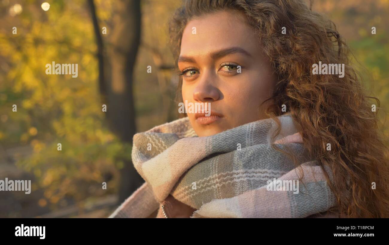Portrait de profil de jolie jeune fille de race blanche aux cheveux bouclés à regarder sérieusement en huis clos dans parc d'automne. Banque D'Images