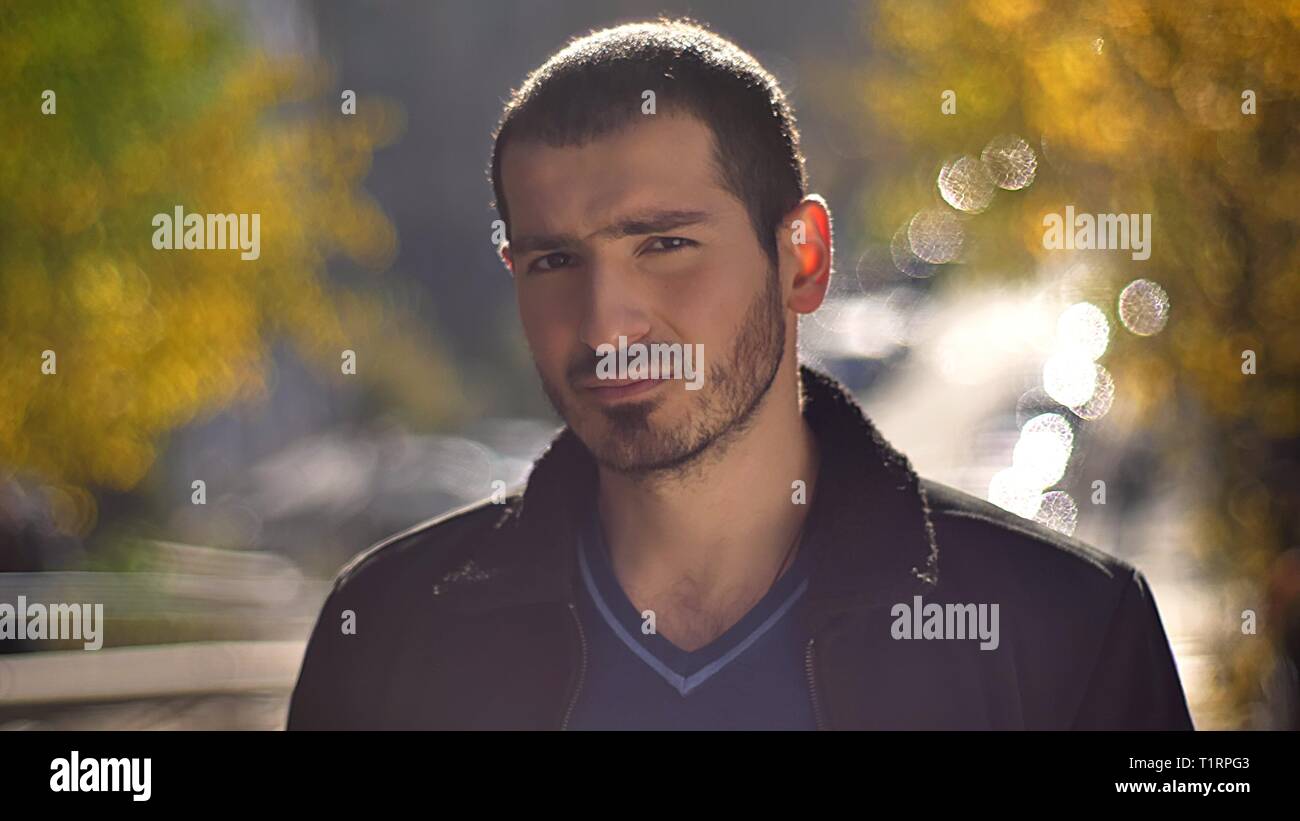 Portrait of caucasian man watching sérieusement en huis clos sur fond de rue d'automne. Banque D'Images