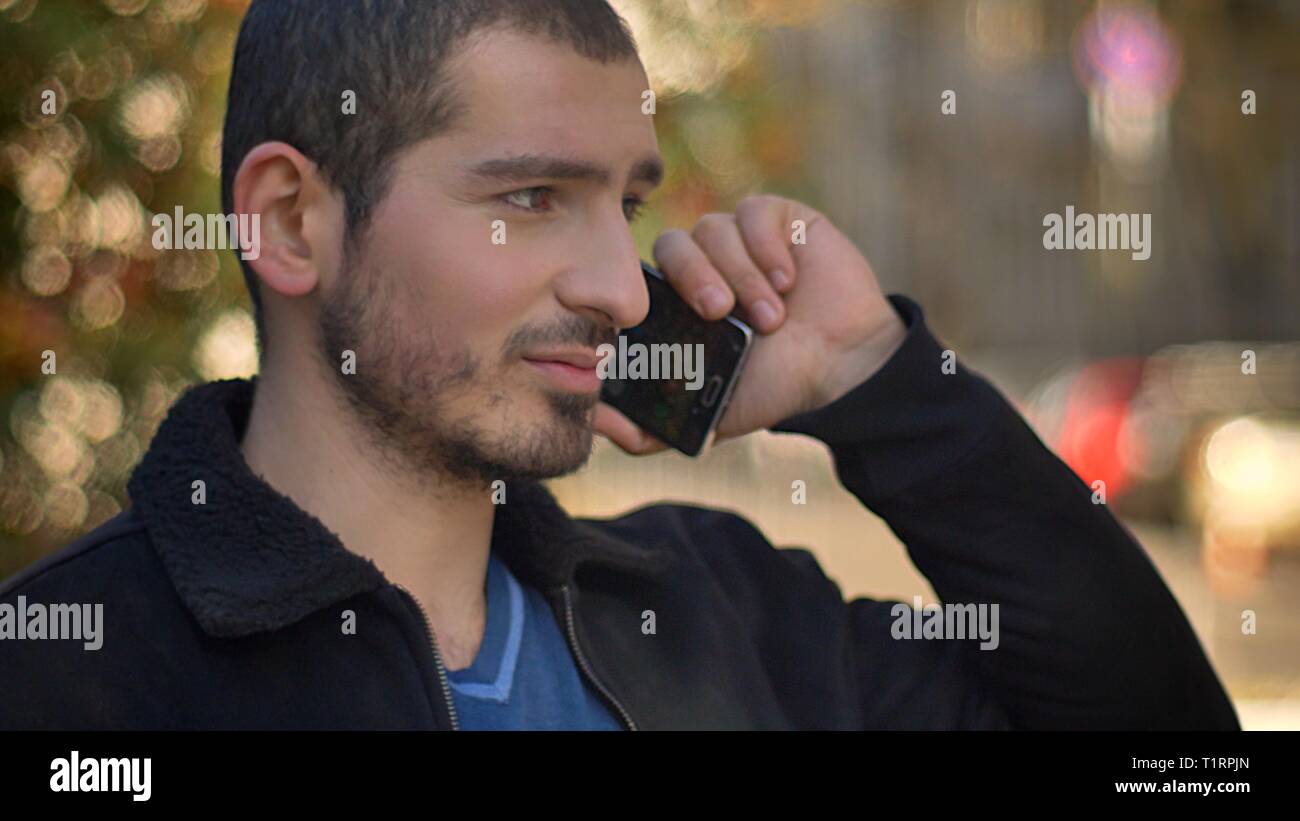 Portrait of caucasian man talking on smartphone et à la rue vers la gauche sur l'arrière-plan. Banque D'Images
