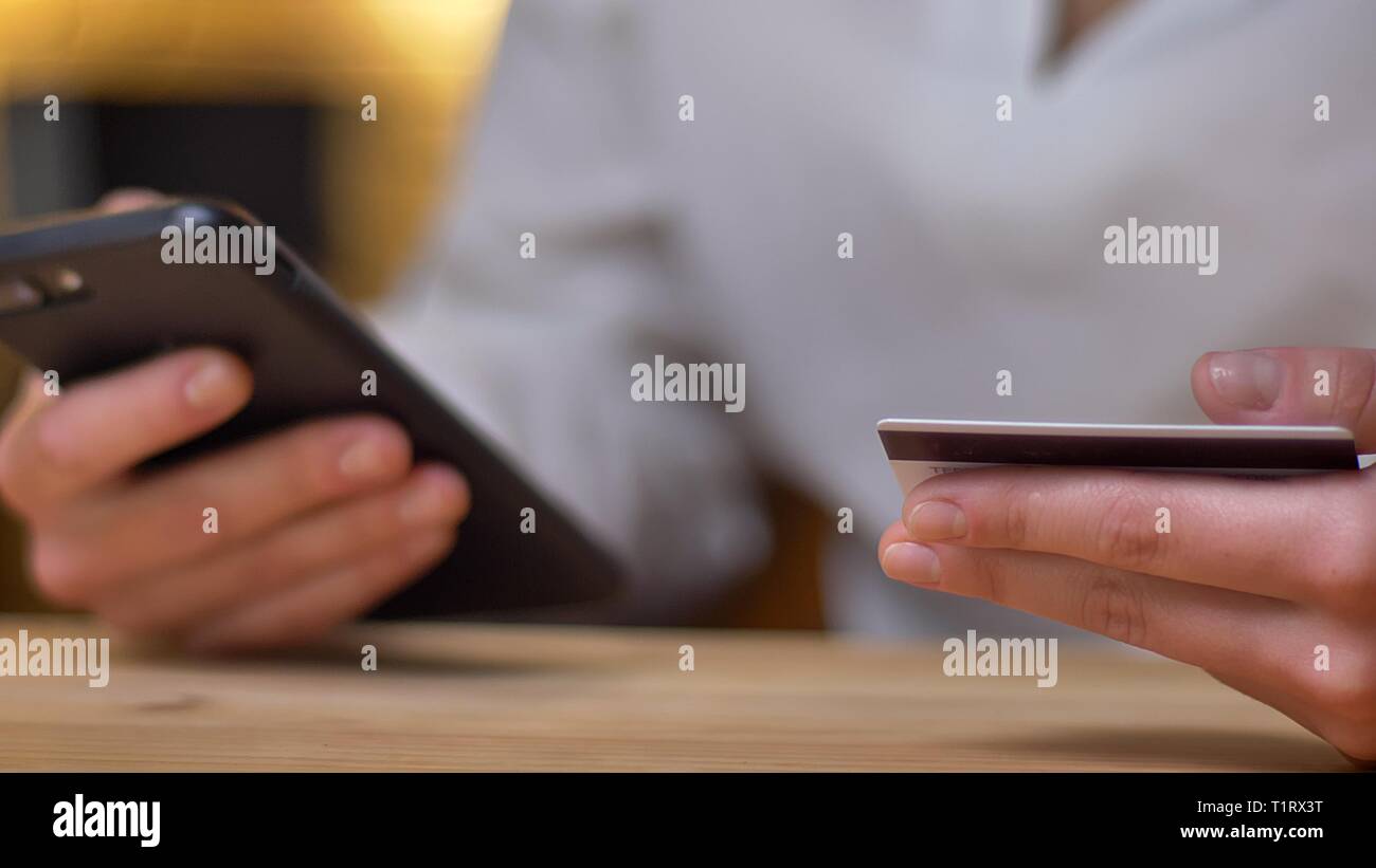 Close-up portrait of young businesswoman faisant les transactions à l'aide de la carte de crédit et sur smartphone. Banque D'Images