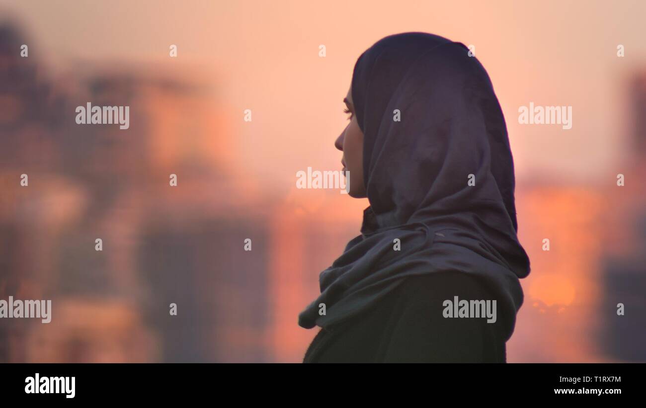 Closeup portrait of young pretty femme en hijab à l'avant avec cadre urbain et bâtiments lumineux sur l'arrière-plan Banque D'Images