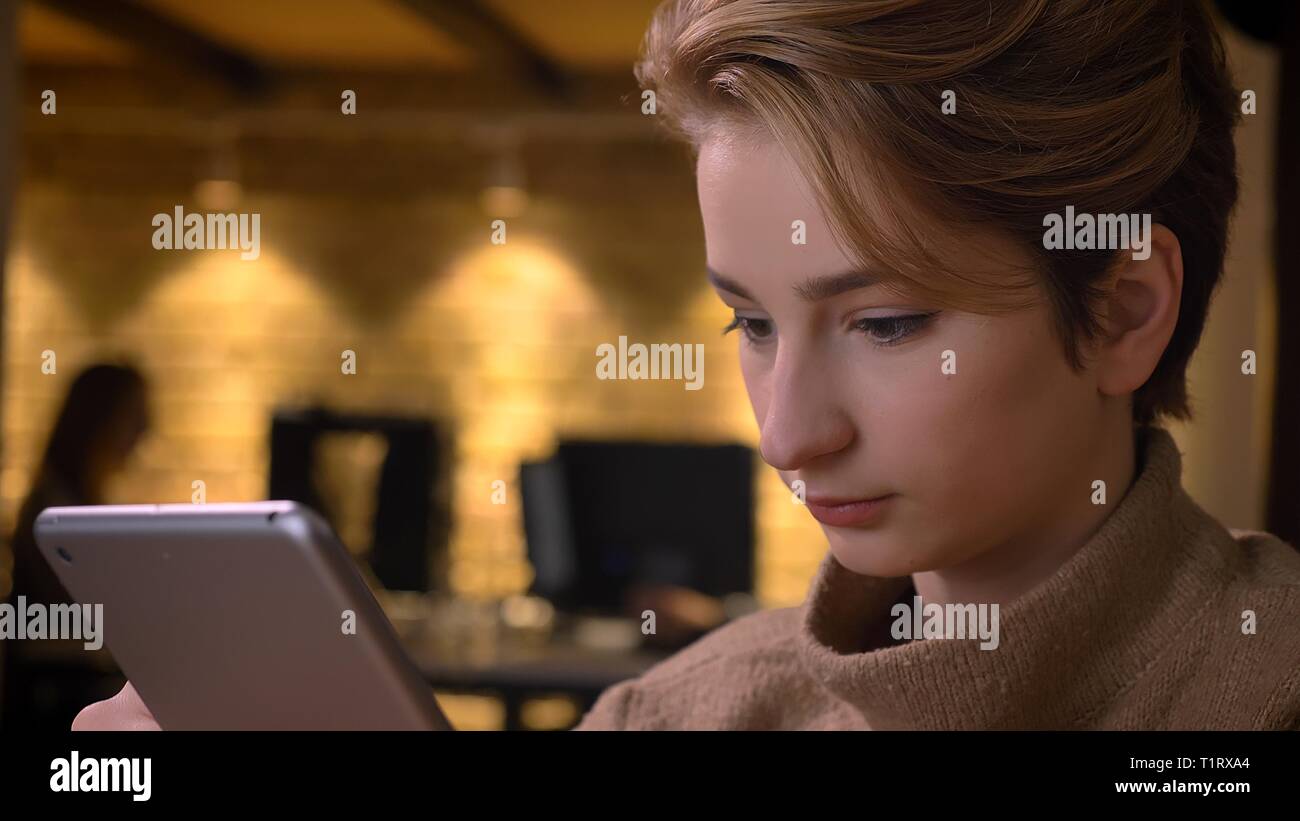 De jeunes pousses Gros plan caucasian businesswoman attrayants à l'aide de la tablette à l'intérieur dans le bureau Banque D'Images