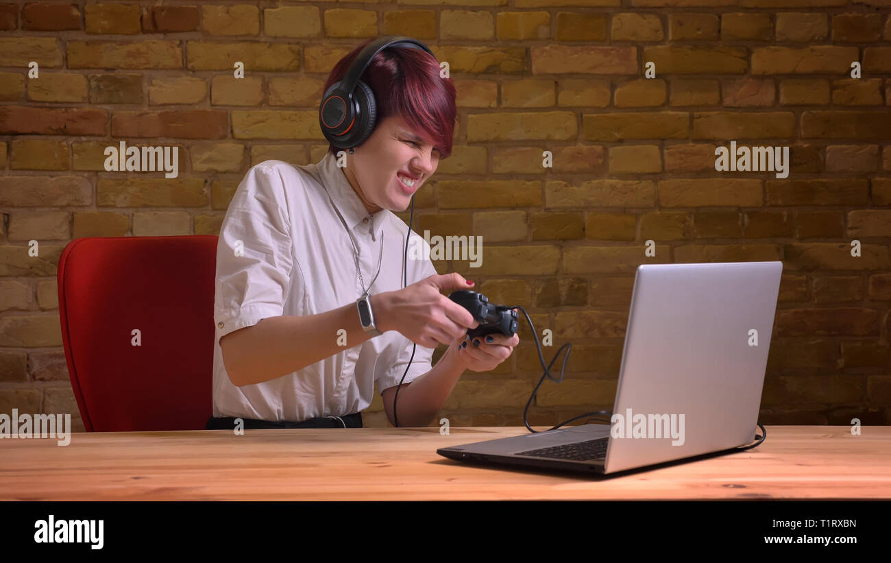 De jeunes pousses Gros plan jolie femelle hipster blogger vidéo de jeux vidéo à l'aide de la console de jeu sur l'ordinateur portable et le streaming heureusement smiling Banque D'Images