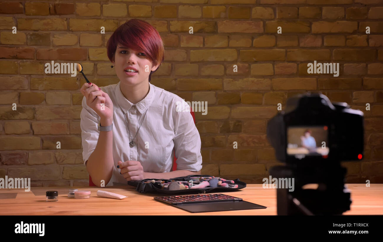 De jeunes pousses Gros plan jolie femelle hipster blogger vidéo live streaming l'application et la promotion des produits de beauté, tout en parlant à la caméra Banque D'Images