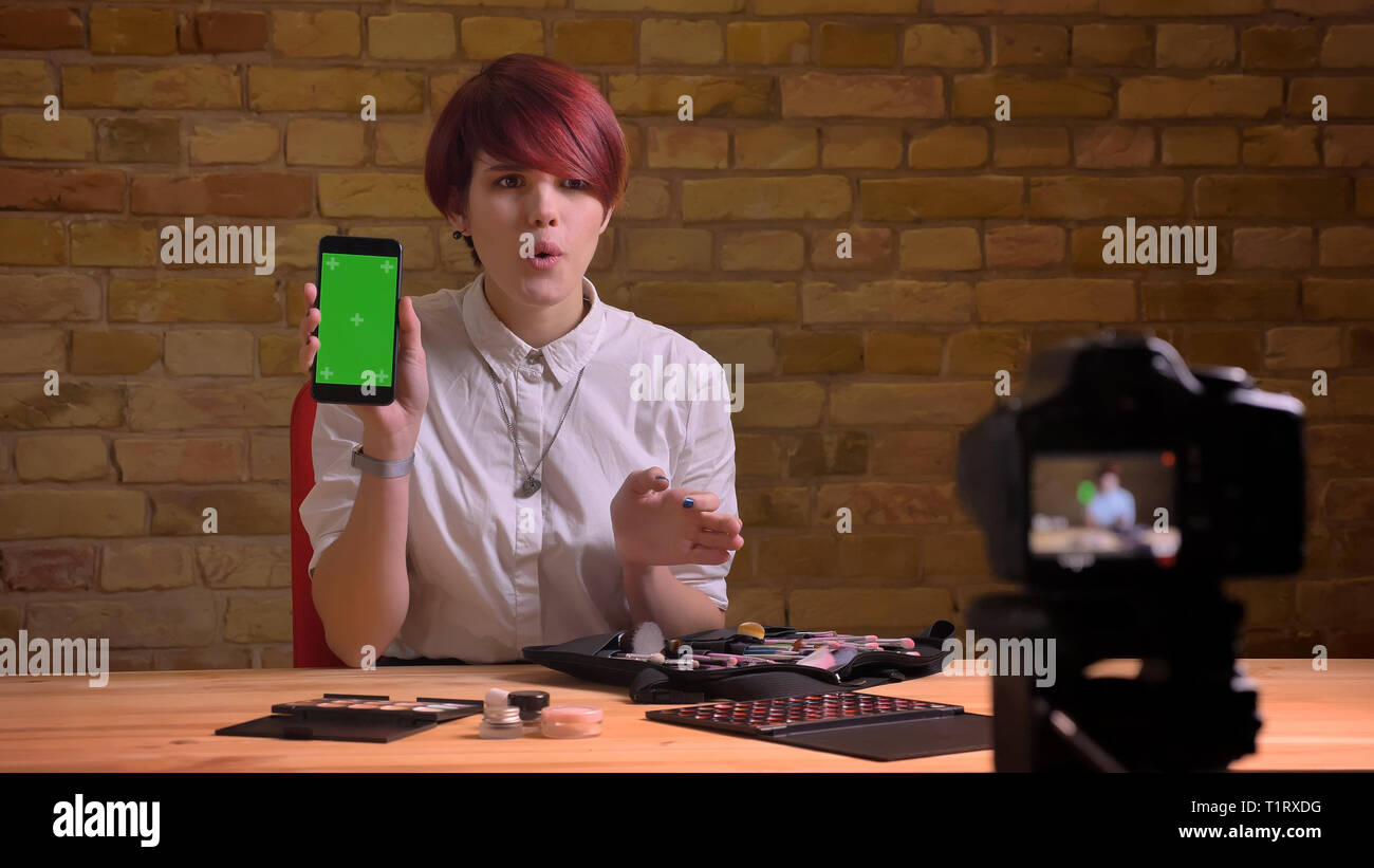 De jeunes pousses Gros plan jolie femelle hipster blogger vidéo live streaming en utilisant la tablette et montrant l'écran de l'appareil photo à chroma vert Banque D'Images