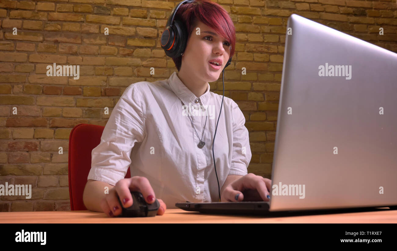 De jeunes pousses Gros plan jolie adolescente videoblogger en live streaming écouteurs lors de l'utilisation de l'ordinateur portable à l'intérieur à la maison Banque D'Images