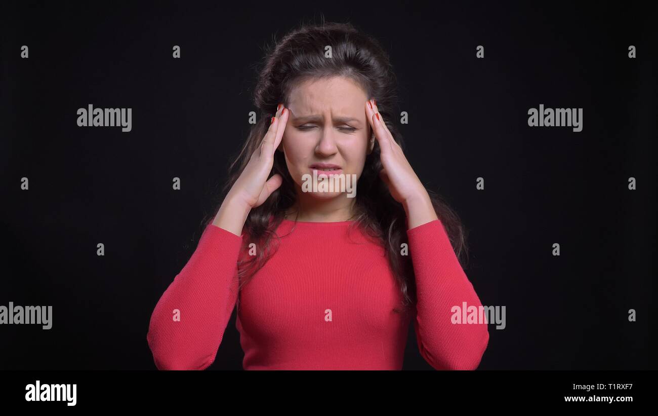 Closeup portrait of attractive middle-aged woman femme ayant un mal de tête en face de la caméra avec isolé sur fond noir Banque D'Images