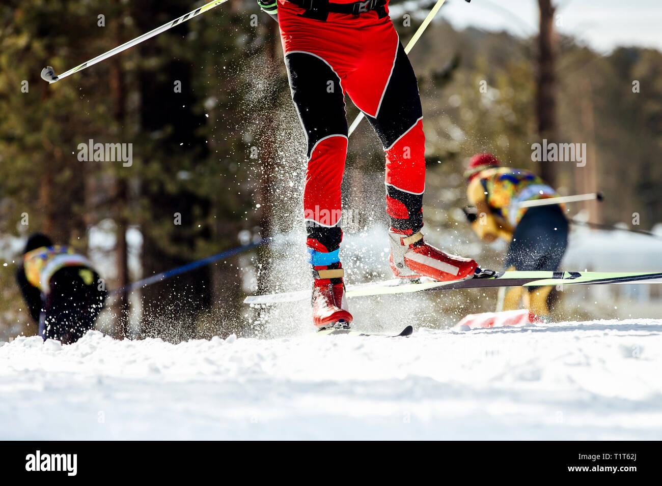 Pieds d'athlète skieur glisse sur neige à partir de la pulvérisation sous des bâtons de ski Banque D'Images