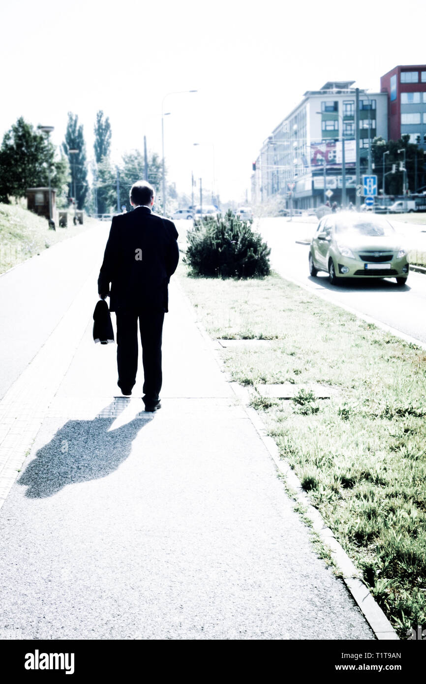 L'homme en costume avec un porte-documents à marcher le long d'un trottoir dans une rue de la ville Banque D'Images