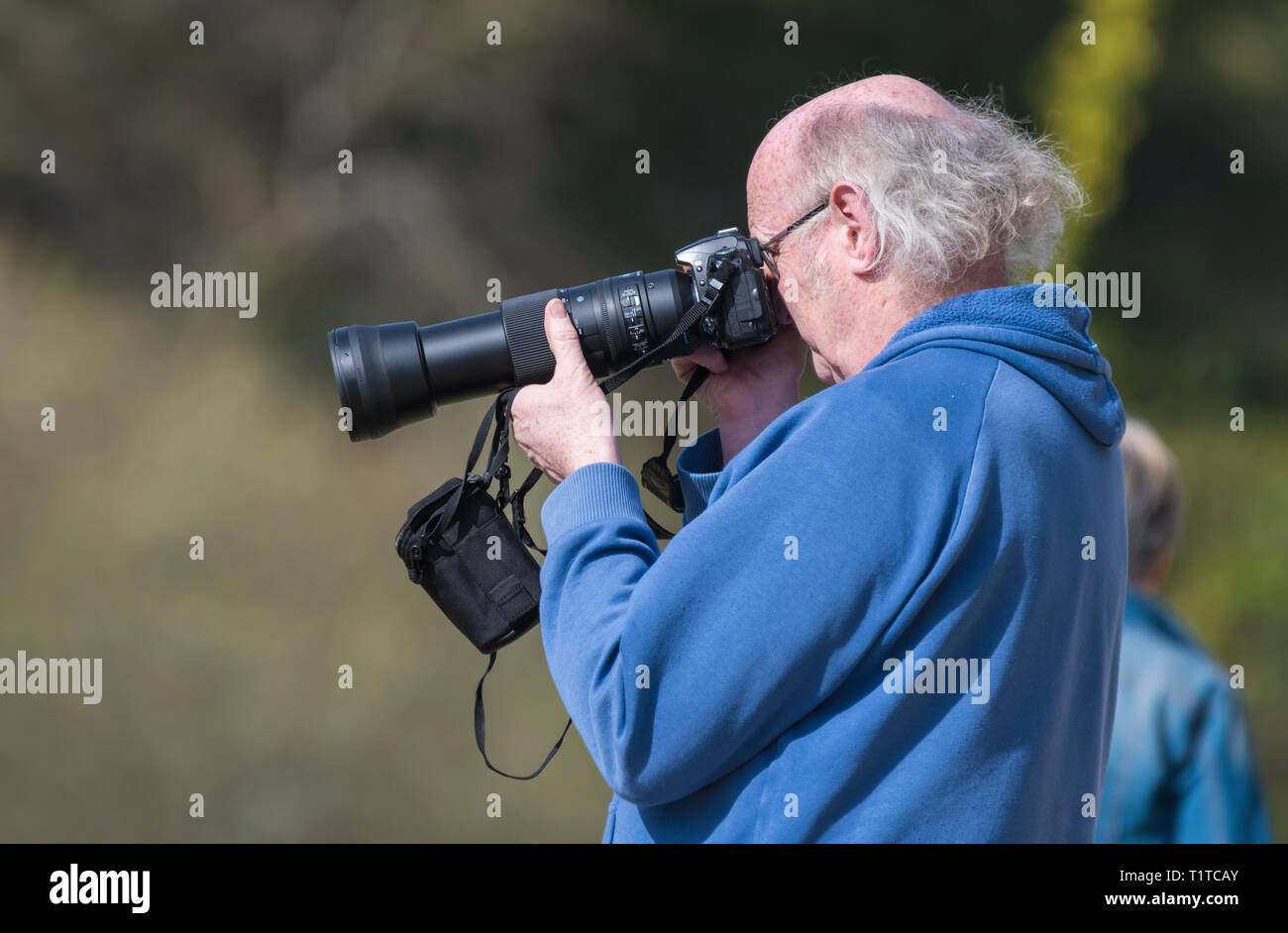 Man photos avec un reflex numérique et téléobjectif. Vue latérale d'homme à prendre des photos avec un appareil photo numérique. Pensionné passe-temps. Banque D'Images