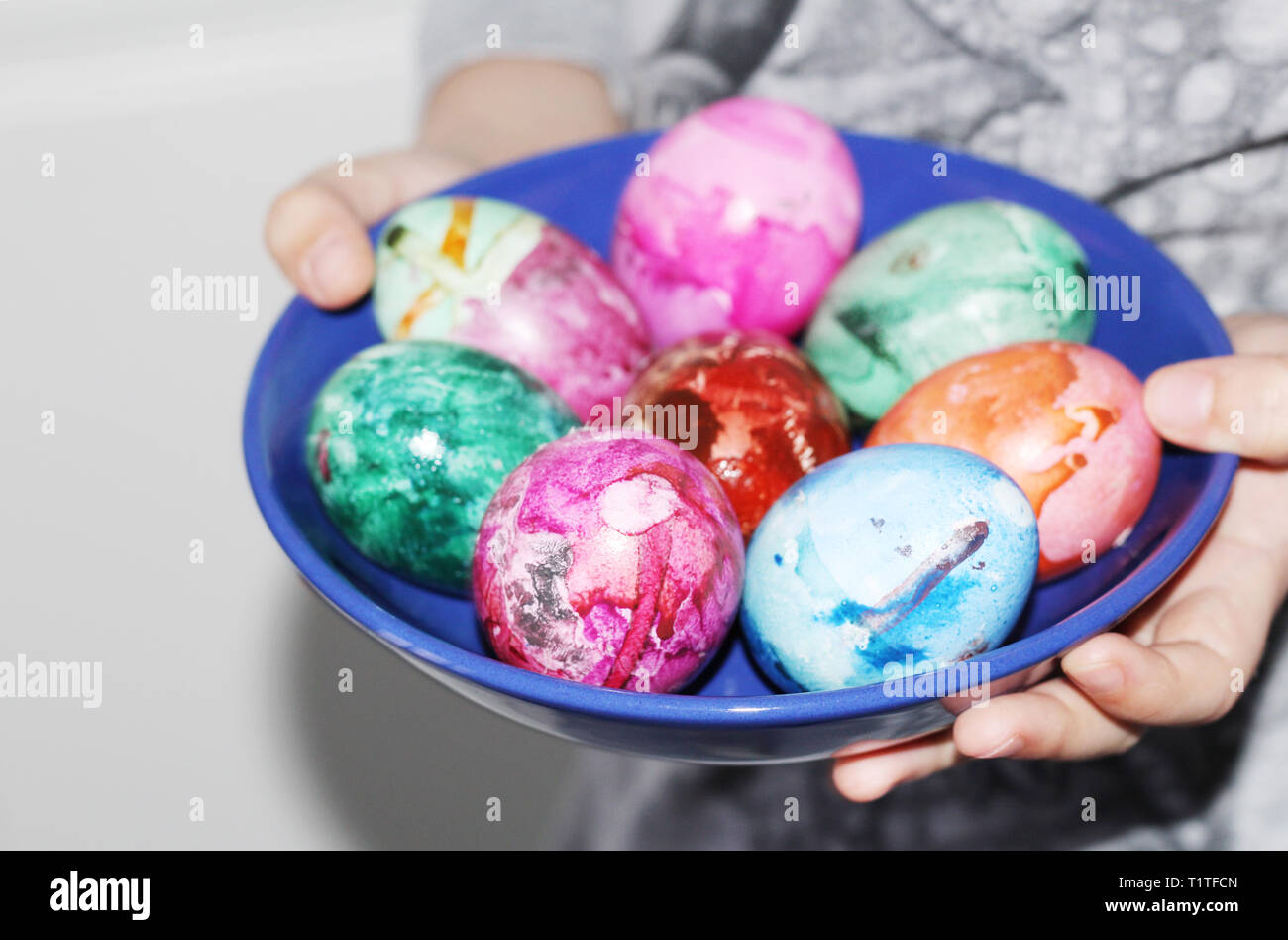 Un enfant dans ses mains tenant une assiette avec des oeufs de Pâques. Peint des oeufs de Pâques. En oeufs colorés. Des tons pastel. Banque D'Images