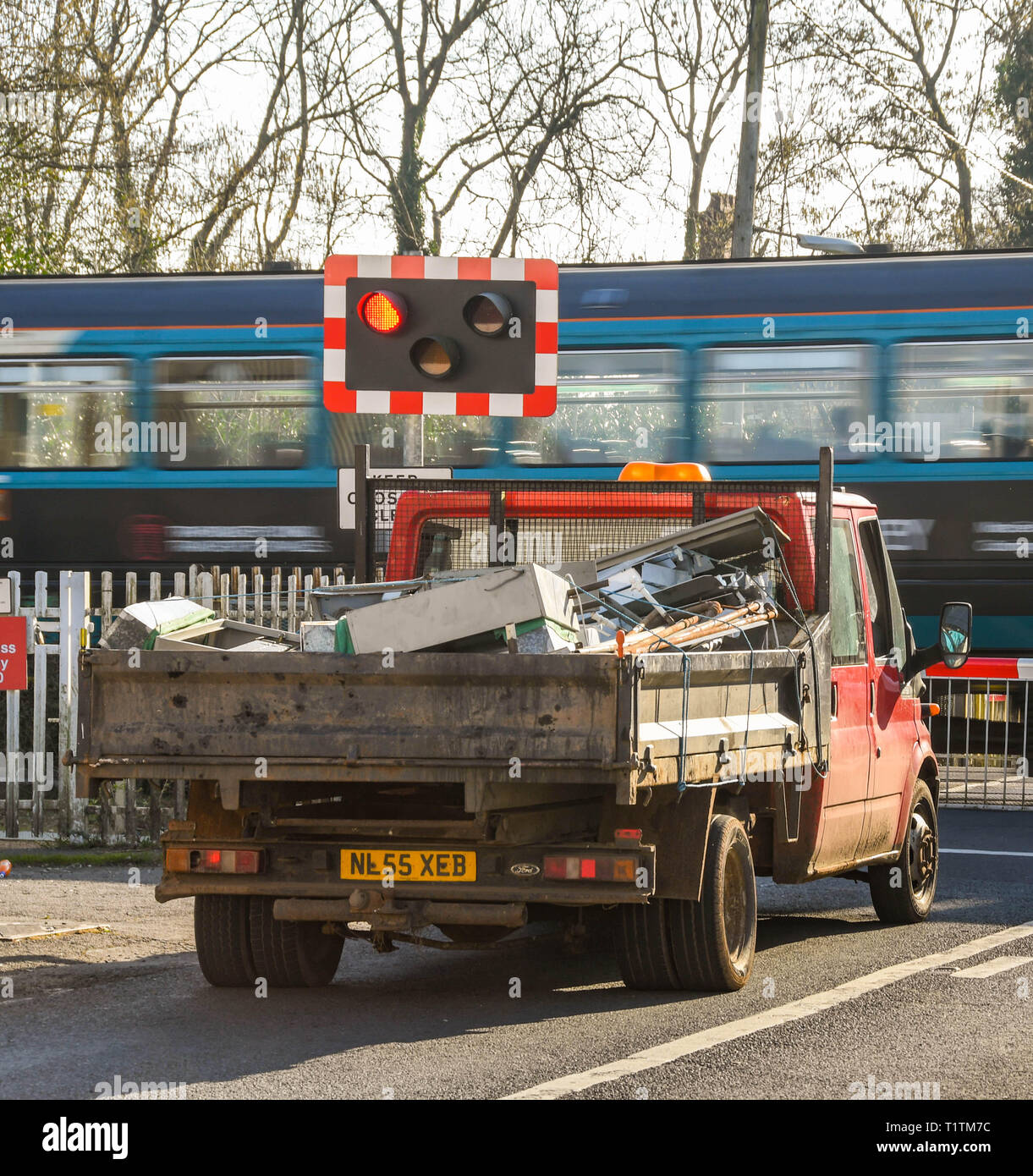 PONTYCLUN, Pays de Galles - Mars 2019 : Camion en attente à la barrière d'un passage à niveau de Pontyclun, Nouvelle-Galles du Sud, tandis qu'un train de banlieue passe. Banque D'Images