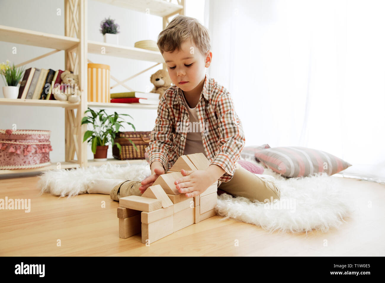 Petit enfant assis sur le plancher. Joli garçon avec des cubes en bois palying à la maison. Image conceptuelle avec l'exemplaire ou l'espace négatif et de mock-up pour votre texte Banque D'Images