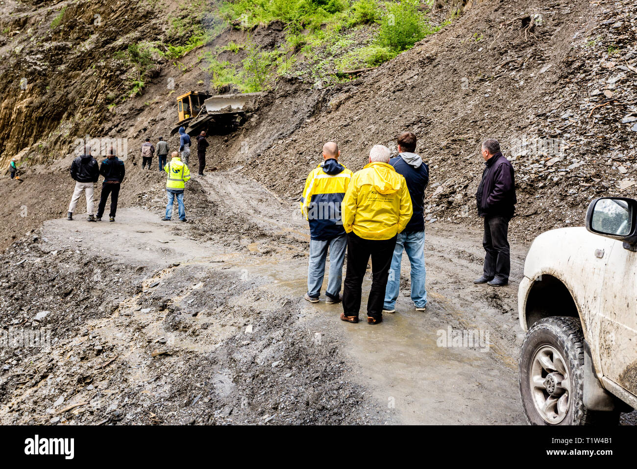 Omalo, Géorgie - 11 juin 2016 : les travailleurs avec le tracteur déposer le glissement de terrain sur la route de montagne, Tusheti Banque D'Images