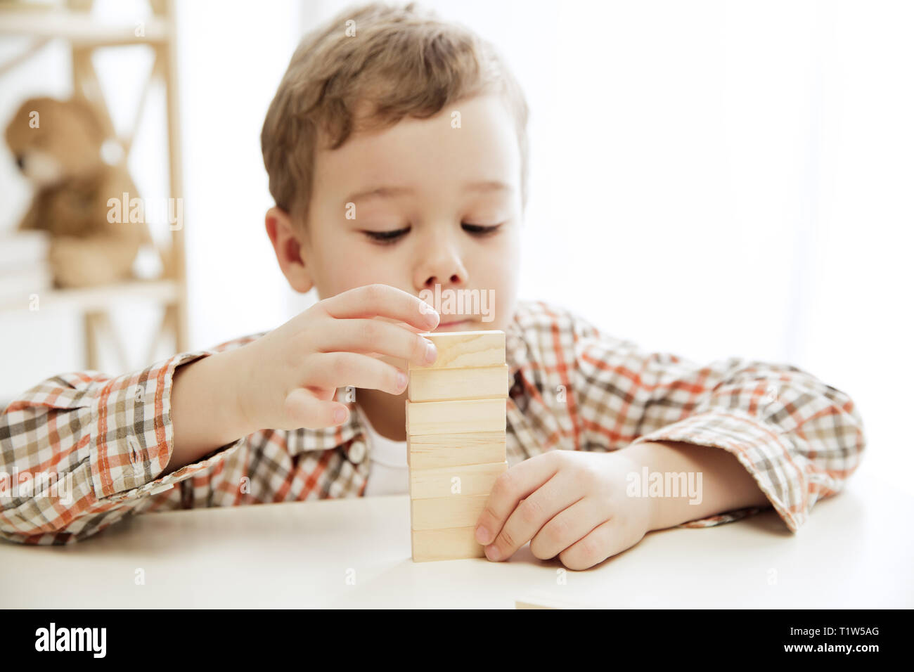 Petit enfant assis sur le plancher. Joli garçon avec des cubes en bois palying à la maison. Image conceptuelle avec l'exemplaire ou l'espace négatif et de mock-up pour votre texte Banque D'Images