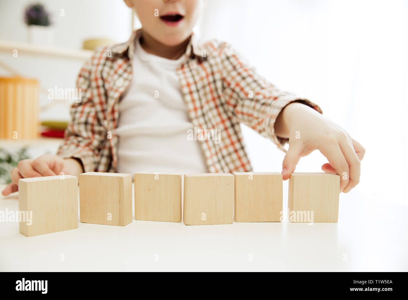 Petit enfant assis sur le plancher. Joli garçon avec des cubes en bois palying à la maison. Image conceptuelle avec l'exemplaire ou l'espace négatif et de mock-up pour votre texte Banque D'Images