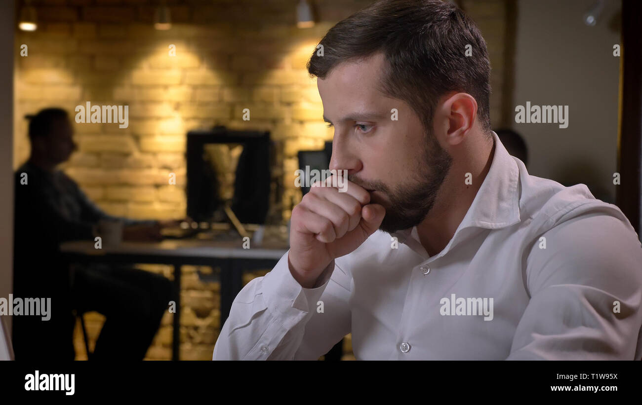 Libre de tirer des profils caucasian businessman typing sur l'ordinateur portable de la toux et d'être mal à l'intérieur dans le bureau Banque D'Images