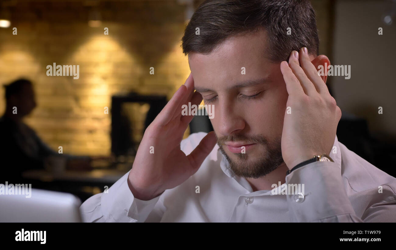 Libre de tirer de l'homme de race blanche adultes employé ayant un mal de tête et beind a souligné et dévasté l'intérieur dans le bureau Banque D'Images