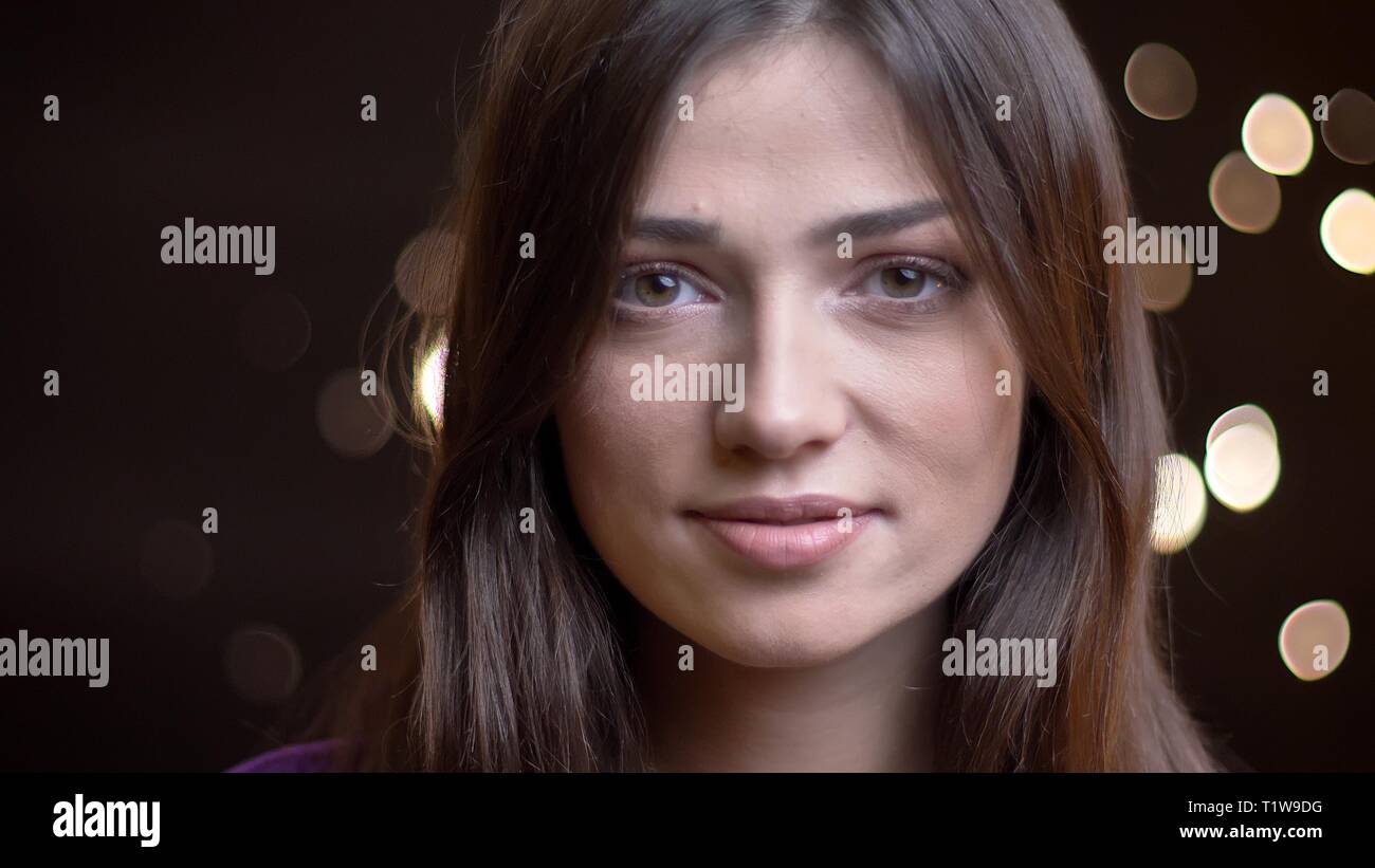 Close-up portrait of beautiful young brunette girl watching calmement en appareil photo de Lumières floues. Banque D'Images