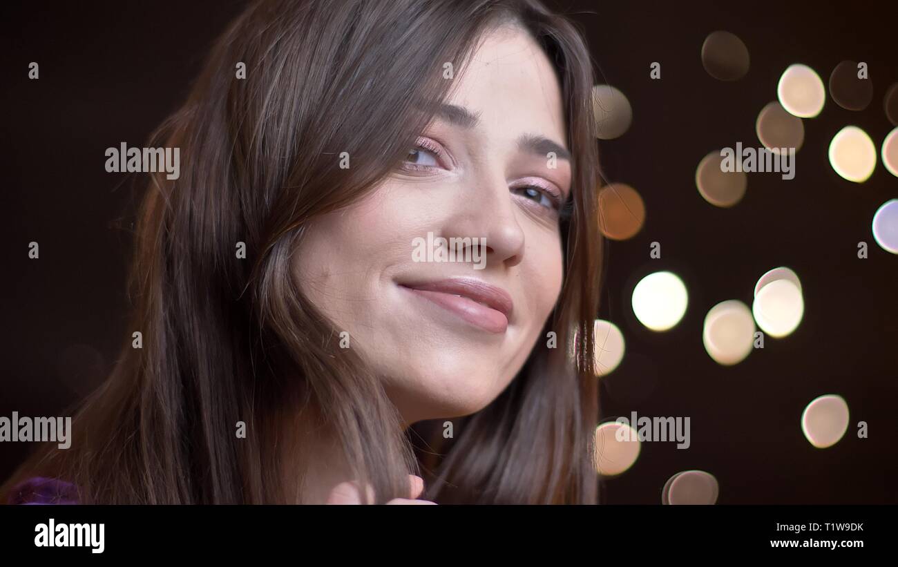 Close-up portrait of caucasian brunette girl regarder curieusement dans l'appareil photo de Lumières floues. Banque D'Images