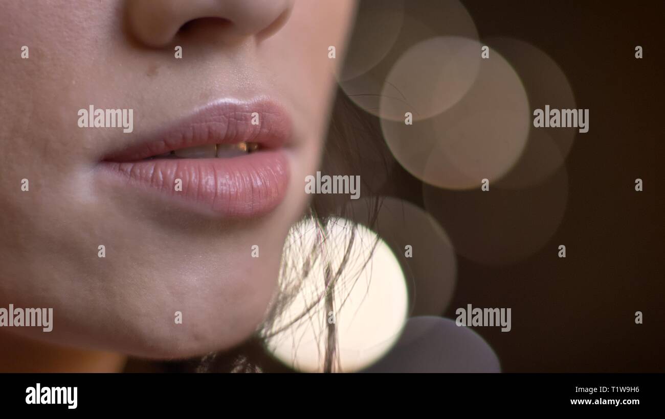 Close-up portrait of caucasian brunette femme lèvres demi-ouvert sur l'arrière-plan Lumières floues. Banque D'Images