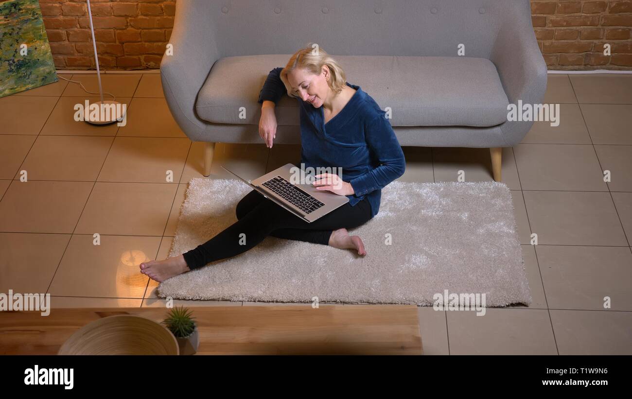 Portrait of young woman sitting on floor et regarder dans coffre joyeusement dans la maison chaleureuse atmosphère. Banque D'Images