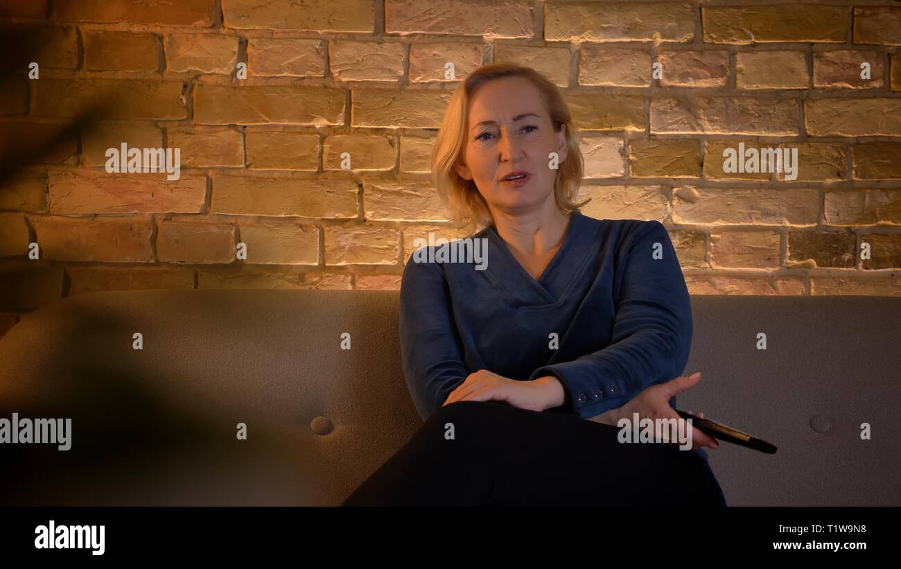 Portrait of senior woman femme assise sur un canapé et regarder la télévision dans la confusion dans un atmosphère familiale. Banque D'Images