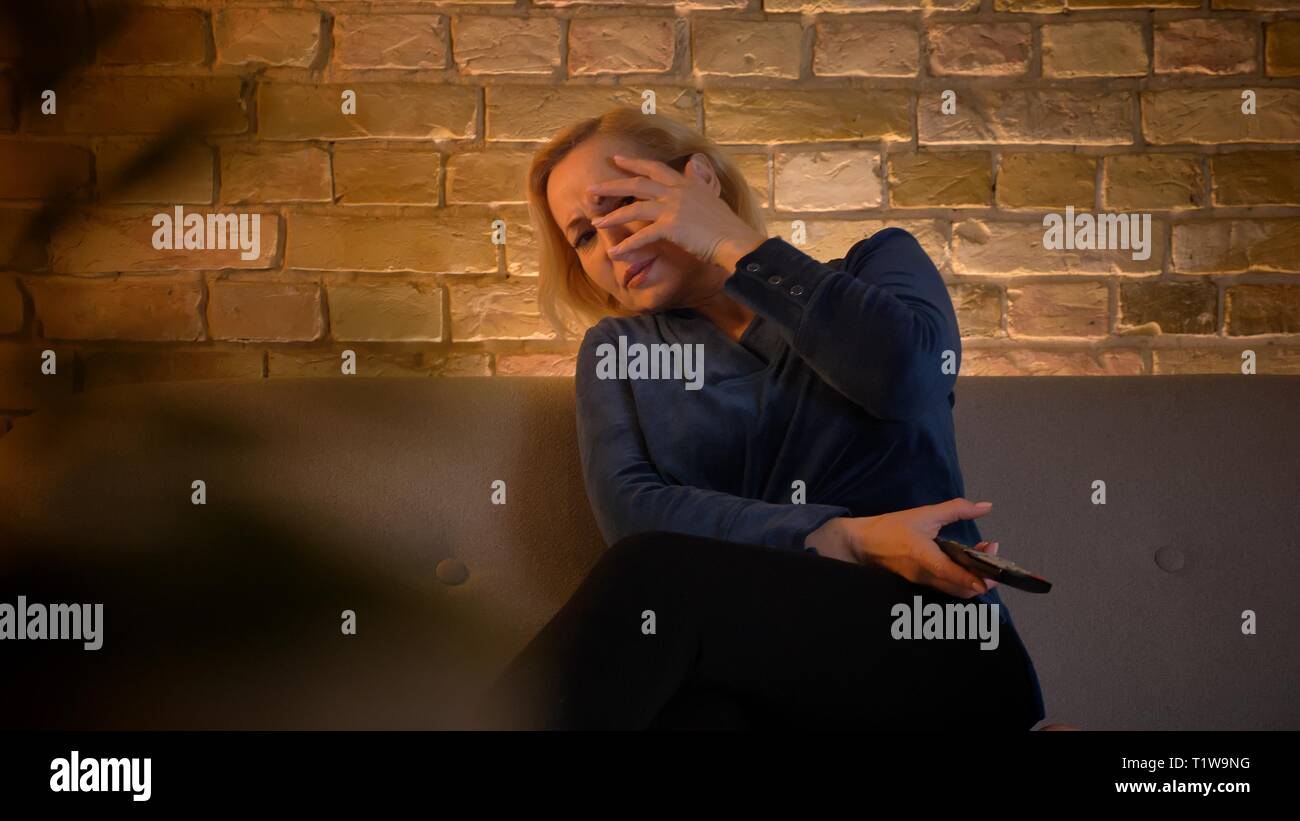 Portrait de peur portrait dame regarder film d'horreur et de se cacher par sa main dans la maison chaleureuse atmosphère. Banque D'Images