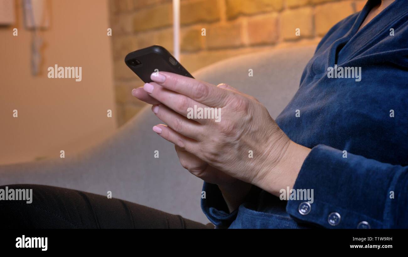 Portrait en gros plan des mains de vieux portrait femme assise sur un canapé dans la maison chaleureuse atmosphère. Banque D'Images