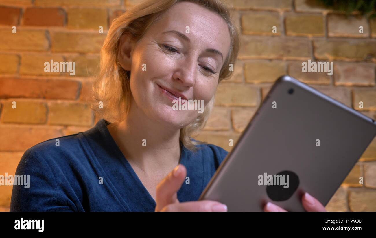 Portrait of young lady travaillant joyeusement avec le comprimé dans l'atmosphère cosy home. Banque D'Images