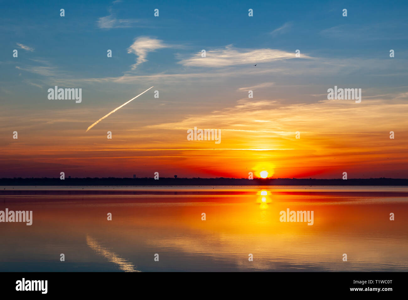 Belle image à l'autre côté du lac Overholser dans l'Oklahoma avec matin lever du soleil sur l'horizon avec des tons bleus et orange. La réflexion du ciel sur l'eau. Banque D'Images