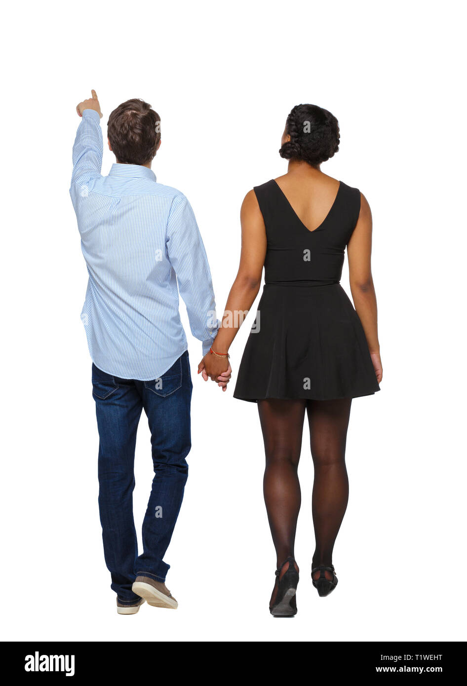 Vue arrière de l'interracial couple qui va quelque part. points marcher friendly girl et Guy se tenant la main. Vue arrière Vue arrière. collection les gens de Banque D'Images