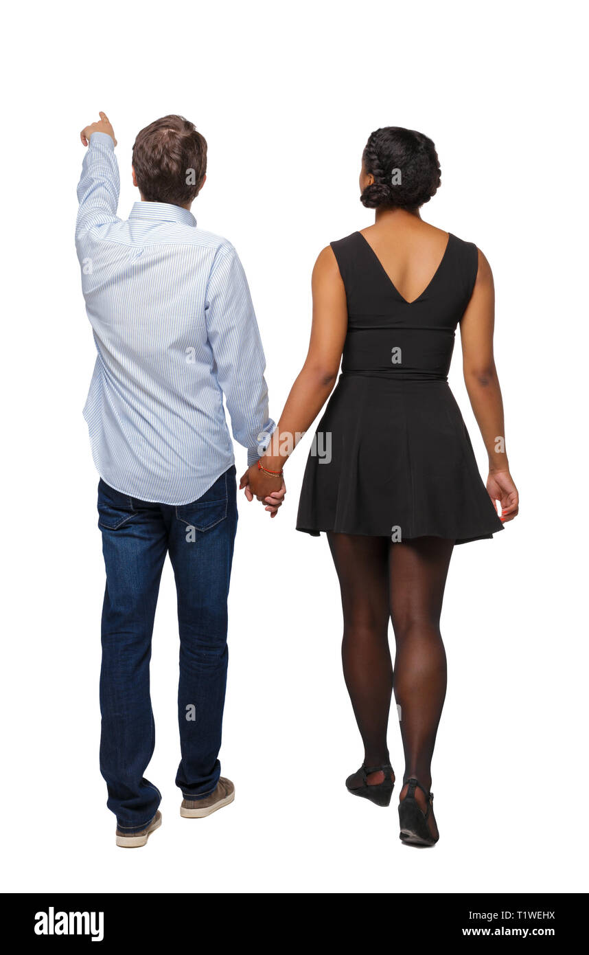 Vue arrière de l'interracial couple qui va quelque part. points marcher friendly girl et Guy se tenant la main. Vue arrière Vue arrière. collection les gens de Banque D'Images