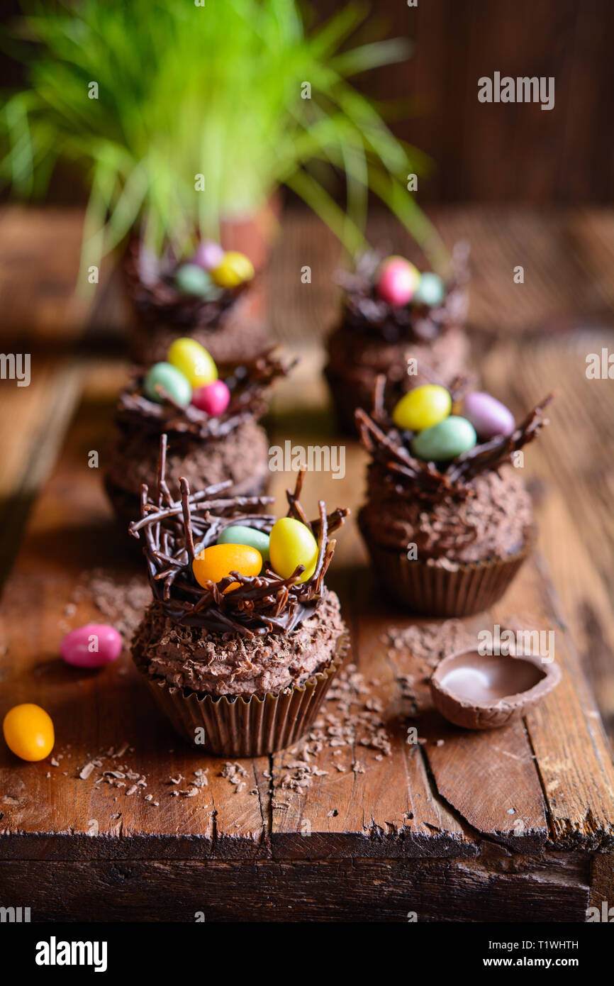 Nid de Pâques au chocolat cupcakes avec de la crème fouettée, décoré avec des oeufs colorés Banque D'Images